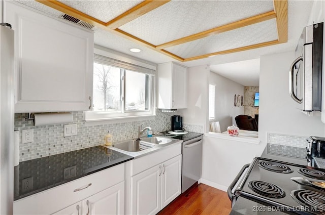 kitchen featuring appliances with stainless steel finishes, decorative backsplash, a sink, and wood finished floors