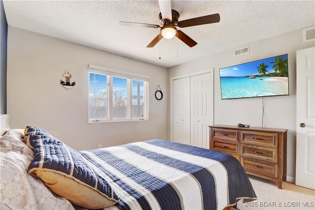 bedroom featuring a ceiling fan, a textured ceiling, visible vents, a closet, and light carpet