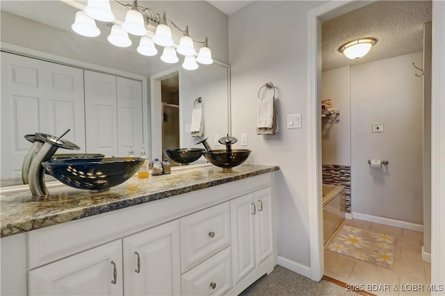 bathroom with a sink, tile patterned floors, baseboards, and double vanity