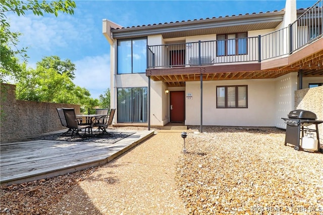 back of property with stucco siding, a balcony, and outdoor dining space