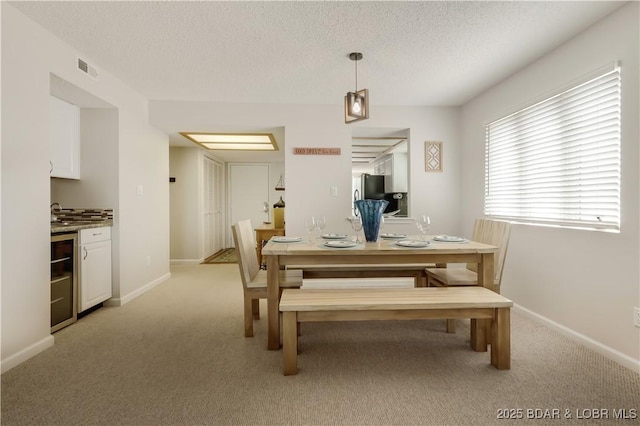 dining space with baseboards, visible vents, a textured ceiling, and light colored carpet