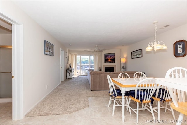 686 Clearwater Dr Unit 1E, Camdenton, MO 65020 - dining room featuring a fireplace, ceiling fan, light colored carpet, and a chandelier