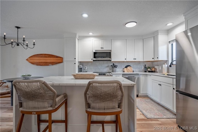 611 Lazy Days Rd Unit F5, Osage Beach, MO 65065 - kitchen featuring tasteful backsplash, white cabinetry, appliances with stainless steel finishes, a kitchen island, and a breakfast bar area