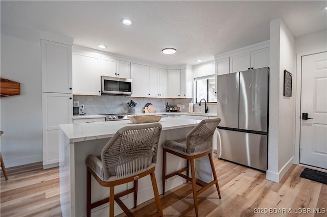 611 Lazy Days Rd Unit F5, Osage Beach, MO 65065 - kitchen with a center island, a sink, light wood-type flooring, stainless steel appliances, and white cabinetry