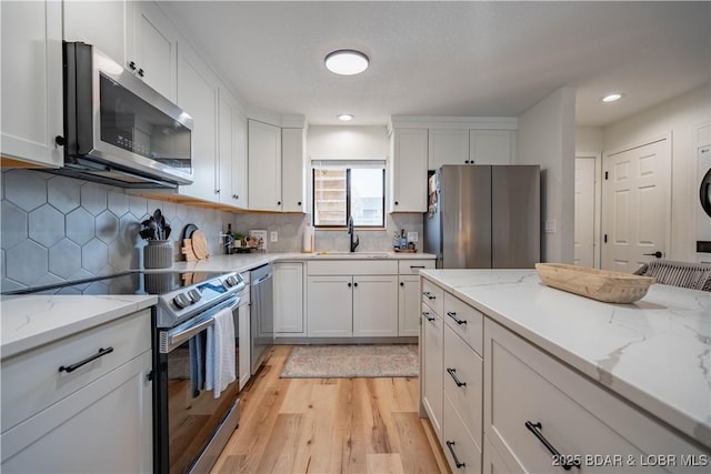 611 Lazy Days Rd Unit F5, Osage Beach, MO 65065 - kitchen with a sink, stainless steel appliances, light wood-style flooring, backsplash, and white cabinetry