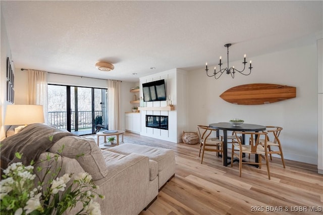 611 Lazy Days Rd Unit F5, Osage Beach, MO 65065 - living room with an inviting chandelier, light wood-style floors, baseboards, a glass covered fireplace, and a textured ceiling