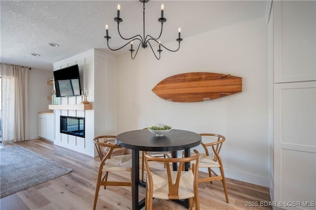 611 Lazy Days Rd Unit F5, Osage Beach, MO 65065 - dining room with a chandelier, a glass covered fireplace, light wood-type flooring, and a textured ceiling