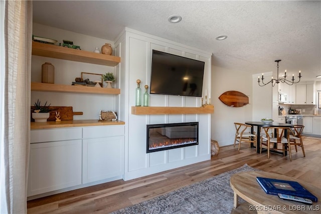 611 Lazy Days Rd Unit F5, Osage Beach, MO 65065 - living area featuring an inviting chandelier, a textured ceiling, a fireplace, and light wood-style floors