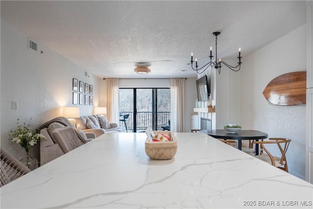 611 Lazy Days Rd Unit F5, Osage Beach, MO 65065 - dining area featuring a textured wall, visible vents, a textured ceiling, and a notable chandelier