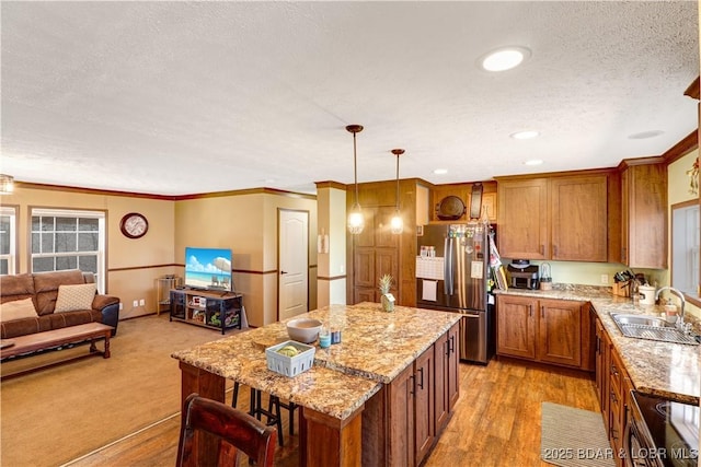 kitchen with brown cabinets, a sink, range, a textured ceiling, and freestanding refrigerator