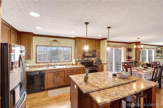 kitchen with a textured ceiling, crown molding, brown cabinets, a sink, and black appliances