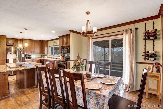 dining area with a textured ceiling, an inviting chandelier, and light wood-type flooring