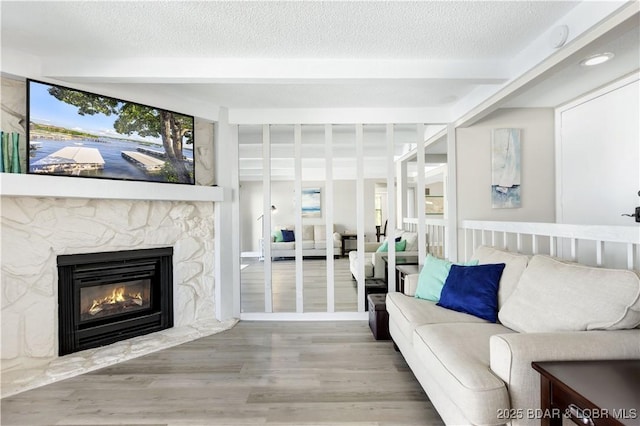 155 Circle Edge Dr Unit 3A, Lake Ozark, MO 65049 - living room featuring beam ceiling, wood finished floors, plenty of natural light, and a stone fireplace