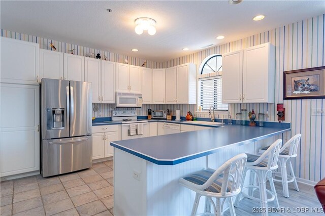 611 Lazy Days Rd Unit L6, Osage Beach, MO 65065 - kitchen with white appliances, a breakfast bar area, white cabinets, a peninsula, and a sink