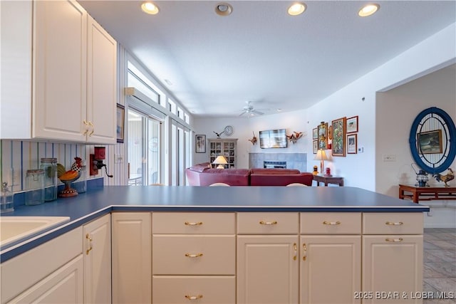 611 Lazy Days Rd Unit L6, Osage Beach, MO 65065 - kitchen featuring a tile fireplace, a ceiling fan, a peninsula, white cabinetry, and recessed lighting