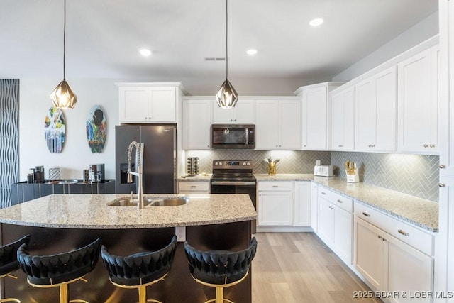 1045 Topsider Ln Unit 113, Osage Beach, MO 65065 - kitchen featuring appliances with stainless steel finishes, light wood-type flooring, white cabinets, tasteful backsplash, and a kitchen bar