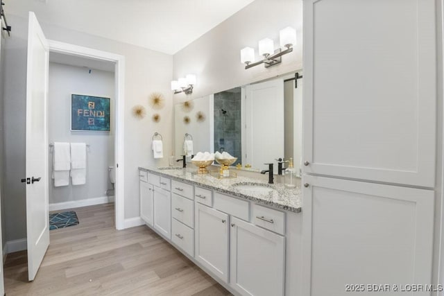 1045 Topsider Ln Unit 113, Osage Beach, MO 65065 - bathroom with double vanity, a stall shower, baseboards, wood finished floors, and toilet