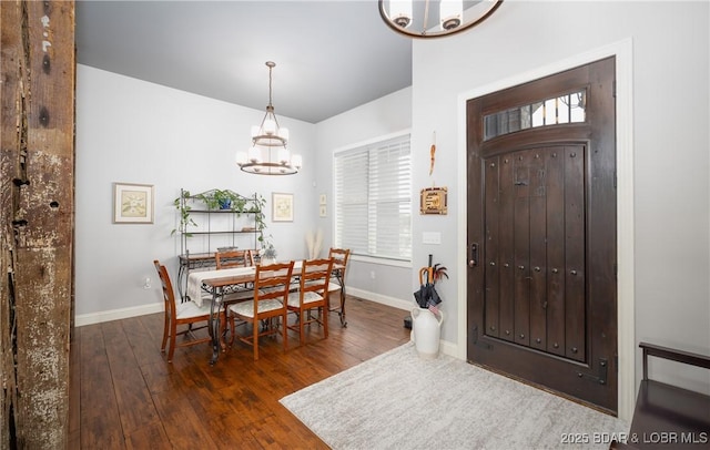 dining space featuring hardwood / wood-style floors, baseboards, and an inviting chandelier