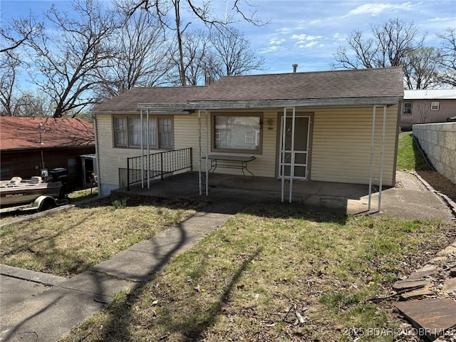 view of front facade with roof with shingles, fence, and a front lawn
