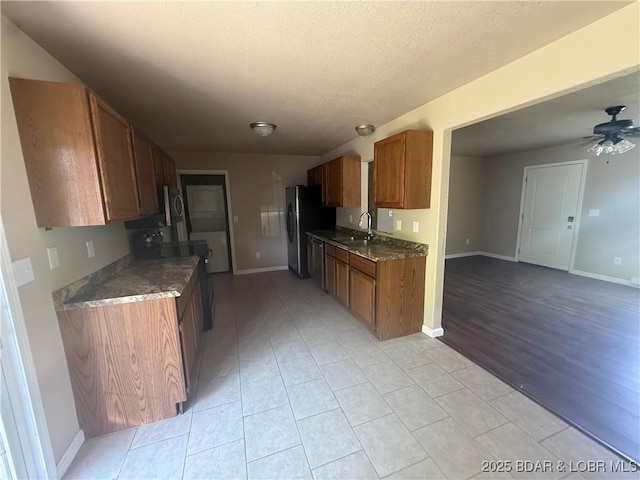 145 Oak Bnd, Kaiser, MO 65047 - kitchen with appliances with stainless steel finishes, brown cabinets, light tile patterned floors, a textured ceiling, and baseboards