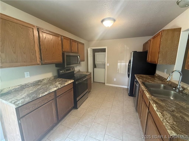 145 Oak Bnd, Kaiser, MO 65047 - kitchen featuring appliances with stainless steel finishes, stacked washer and clothes dryer, a sink, brown cabinetry, and a textured ceiling