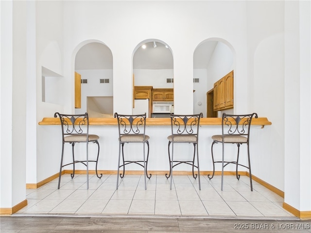 3760 Dogwood Dr, Stover, MO 65078 - kitchen with brown cabinetry, baseboards, white appliances, visible vents, and a kitchen breakfast bar