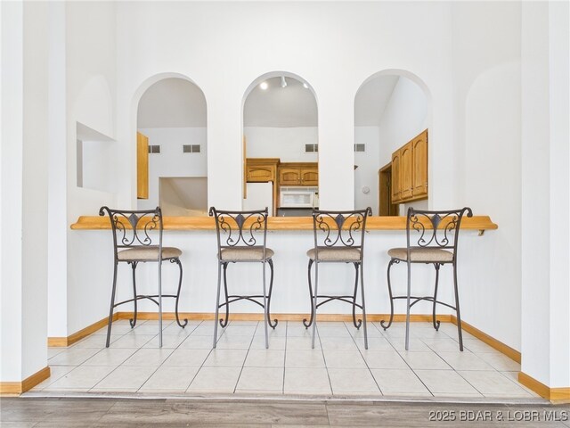 3760 Dogwood Dr, Stover, MO 65078 - kitchen with a breakfast bar, brown cabinetry, visible vents, baseboards, and white appliances