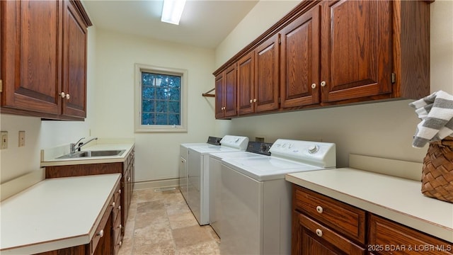 washroom featuring a sink, cabinet space, independent washer and dryer, and baseboards