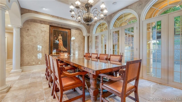 dining area featuring decorative columns, an inviting chandelier, french doors, visible vents, and stone tile flooring