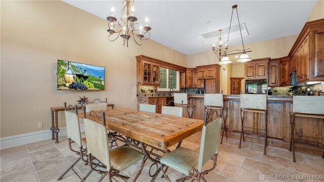 dining area featuring baseboards, stone finish floor, a tray ceiling, and an inviting chandelier