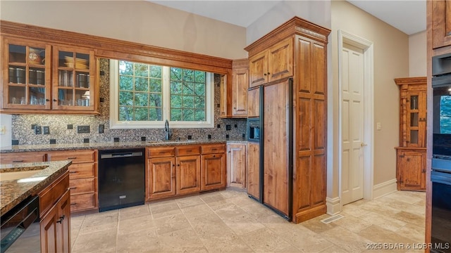 kitchen featuring dishwasher, a sink, dark stone counters, and brown cabinets