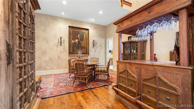 dining area featuring a bar, recessed lighting, baseboards, and wood finished floors