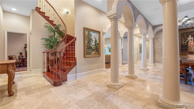 entryway featuring stairs, a towering ceiling, baseboards, and stone finish flooring