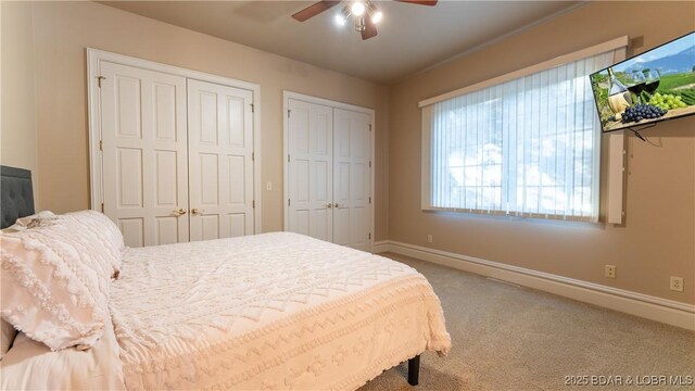 bedroom with two closets, carpet floors, baseboards, and ceiling fan