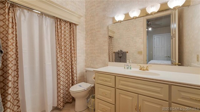 bathroom featuring vanity, toilet, wallpapered walls, ensuite bath, and ceiling fan