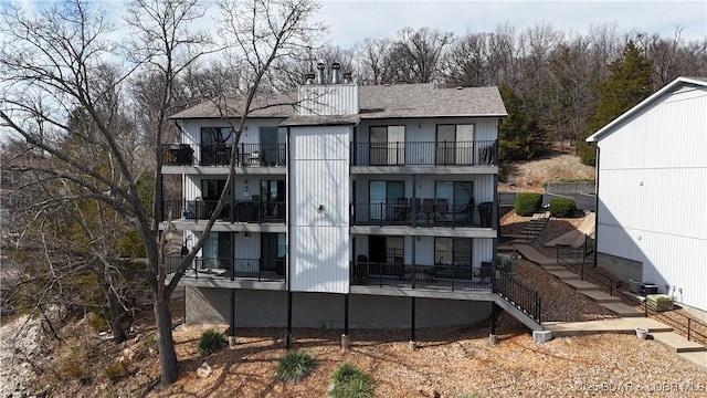 31347 Northshore Dr Unit 101A, Rocky Mount, MO 65072 - back of house featuring stairs, roof with shingles, a chimney, a balcony, and central AC