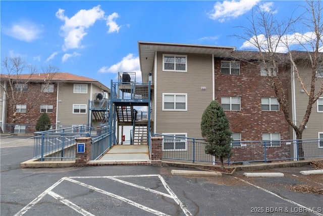 view of building exterior with uncovered parking, stairway, and fence