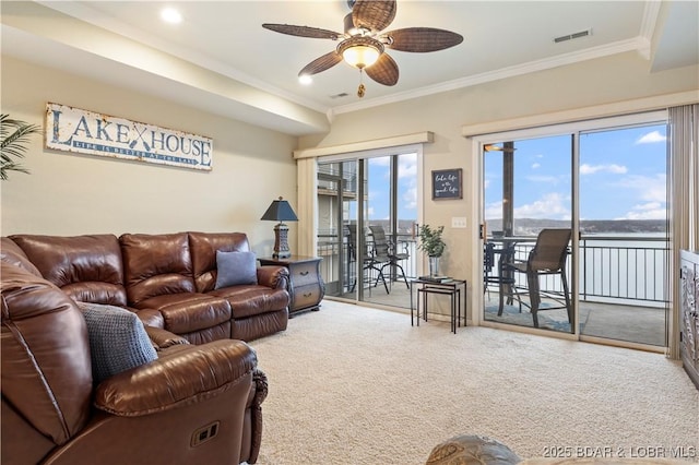 carpeted living room with a ceiling fan and crown molding