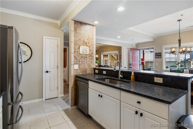 kitchen with a sink, appliances with stainless steel finishes, crown molding, white cabinetry, and light tile patterned flooring