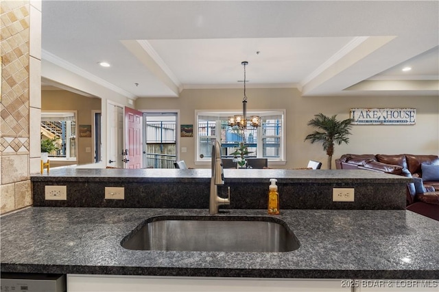 kitchen with open floor plan, a sink, crown molding, dark stone countertops, and a chandelier