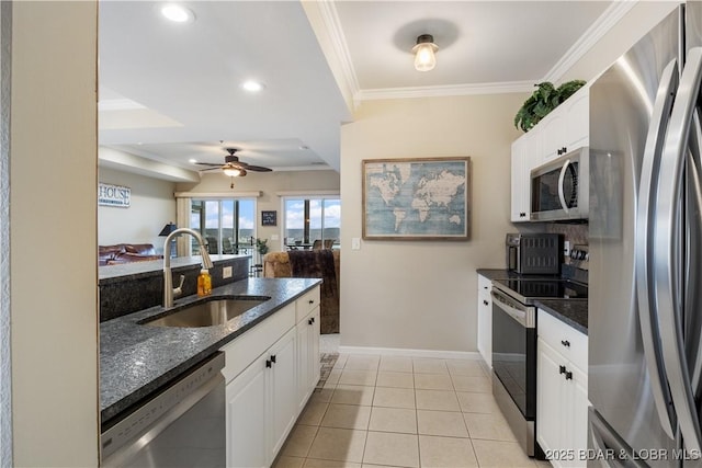 kitchen with stainless steel appliances, a sink, dark stone countertops, baseboards, and white cabinetry