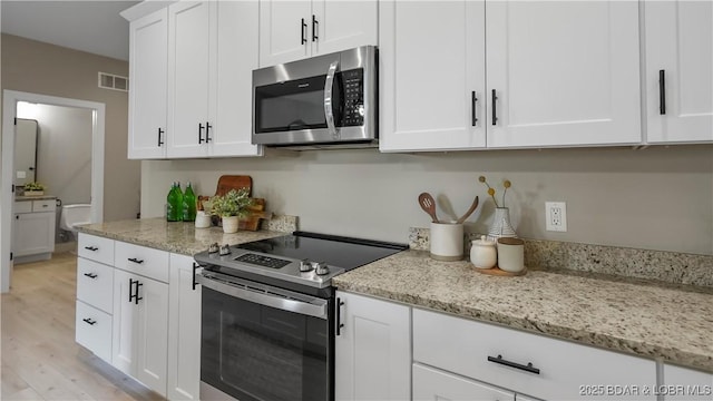 20311 Timberlake Village Ln, Rocky Mount, MO 65072 - kitchen with white cabinetry, visible vents, light wood-style flooring, light stone countertops, and appliances with stainless steel finishes