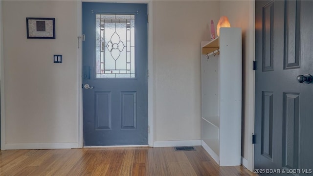 foyer entrance with baseboards, visible vents, and wood finished floors