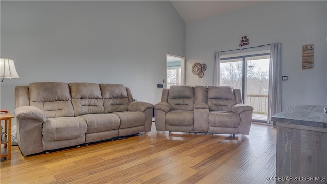 living room with high vaulted ceiling and light wood-style flooring