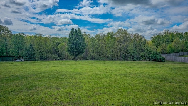view of yard featuring a view of trees and fence