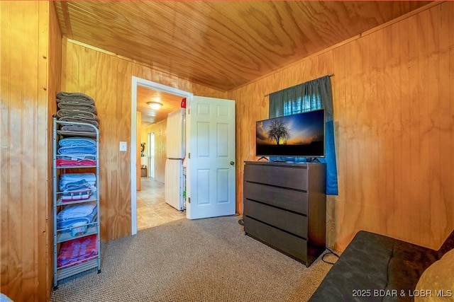 carpeted bedroom with wooden ceiling, wood walls, and freestanding refrigerator