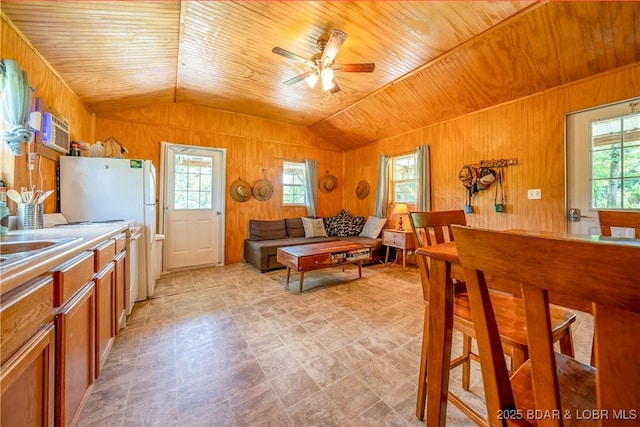 living area with a ceiling fan, a healthy amount of sunlight, and wooden walls