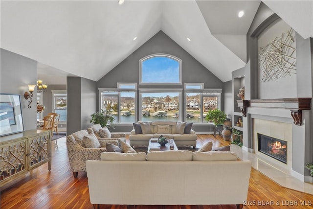 living area with a tile fireplace, high vaulted ceiling, wood finished floors, and recessed lighting