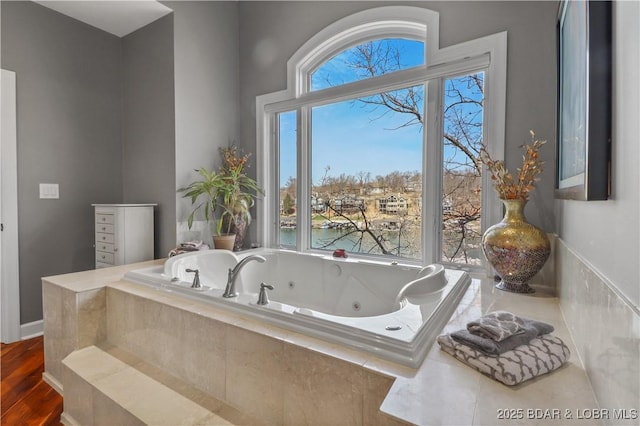 full bath with a tub with jets and wood finished floors