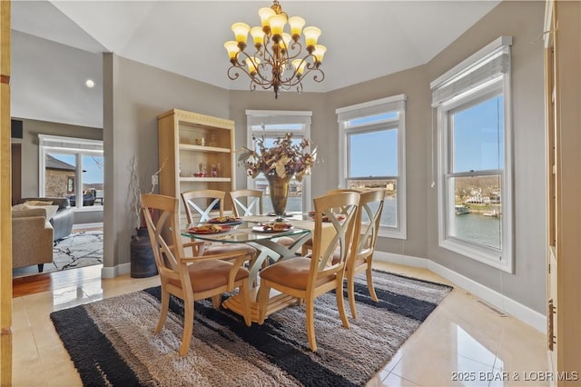 dining space with a chandelier, light tile patterned floors, and baseboards
